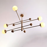 Aurelia 5 light linear globe chandelier installed above a bedroom with warm ambient lighting and modern brass detailing