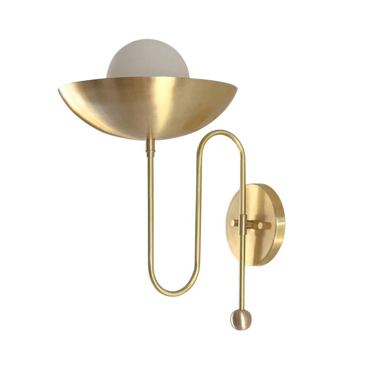 Angled view of the Aurora modern brass bowl wall sconce featuring a sculptural bowl-shaped shade, frosted globe diffuser, and elegant loop arm.