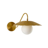 Close-up view of the Aurora modern brass wall sconce highlighting the flower-inspired metal shade, frosted globe diffuser, and minimalist curved frame.