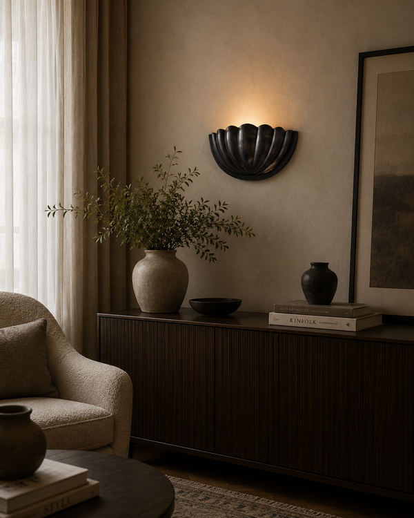 Aurora modern gunmetal fluted half bowl wall sconce installed in a contemporary living room, providing warm indirect ambient illumination above a dark wood console.