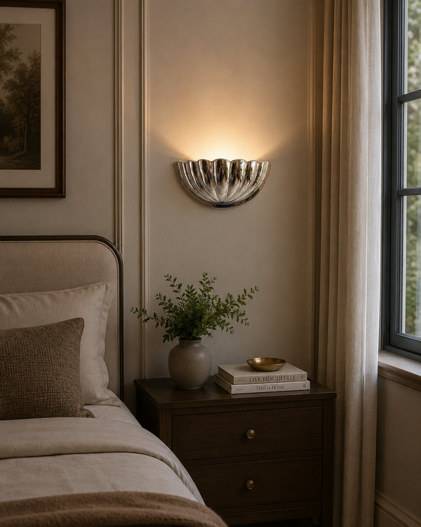 Aurora modern polished nickel fluted half bowl wall sconce installed in a contemporary bedroom, casting warm indirect ambient light above a bedside table.