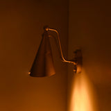 Double cone wall sconce used as bedroom accent lighting with warm glow, curved arms, and refined brass detailing