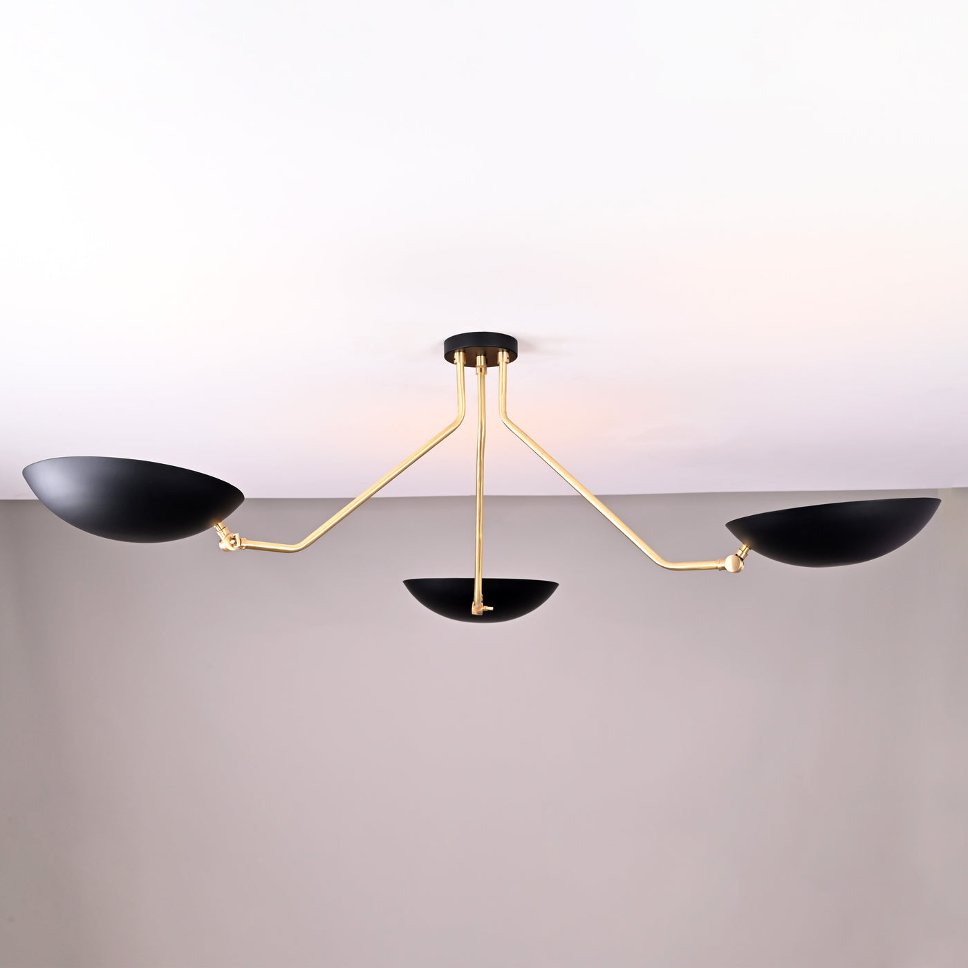 Front view of modern black and brass 3-light bowl chandelier with sculptural arms and matte black shades.