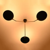 Bottom glowing view of black bowl chandelier illuminating the ceiling with warm ambient light and stylish brass arms.