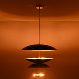 Black and brass disc chandelier showing illuminated lower bowl with soft diffused light