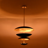 Installed black and brass disc chandelier creating warm ambient indirect lighting in a modern interior