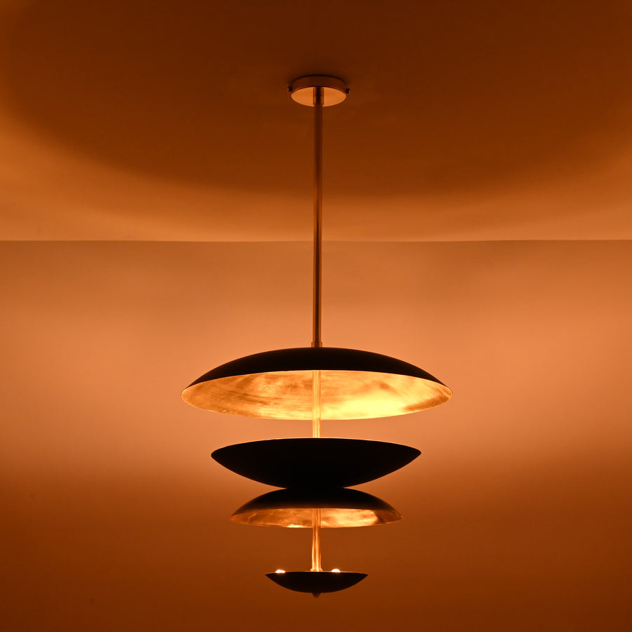 Layered black and brushed brass disc chandelier with warm indirect lighting, modern industrial ceiling light handcrafted by Brass Leaf Studio