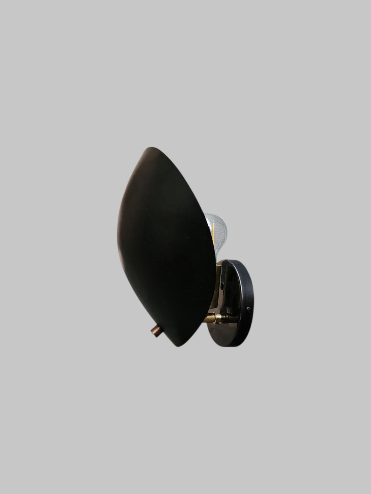 Black brass leaf-shaped wall sconce with bulb partially visible
