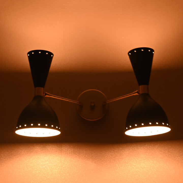 Double cone brass wall sconce with upward and downward warm glow in dark ambiance