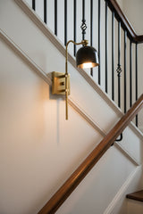 Black brass sheet shade wall sconce with brass patina arm and backplate for bedroom, bathroom, and hallway lighting
