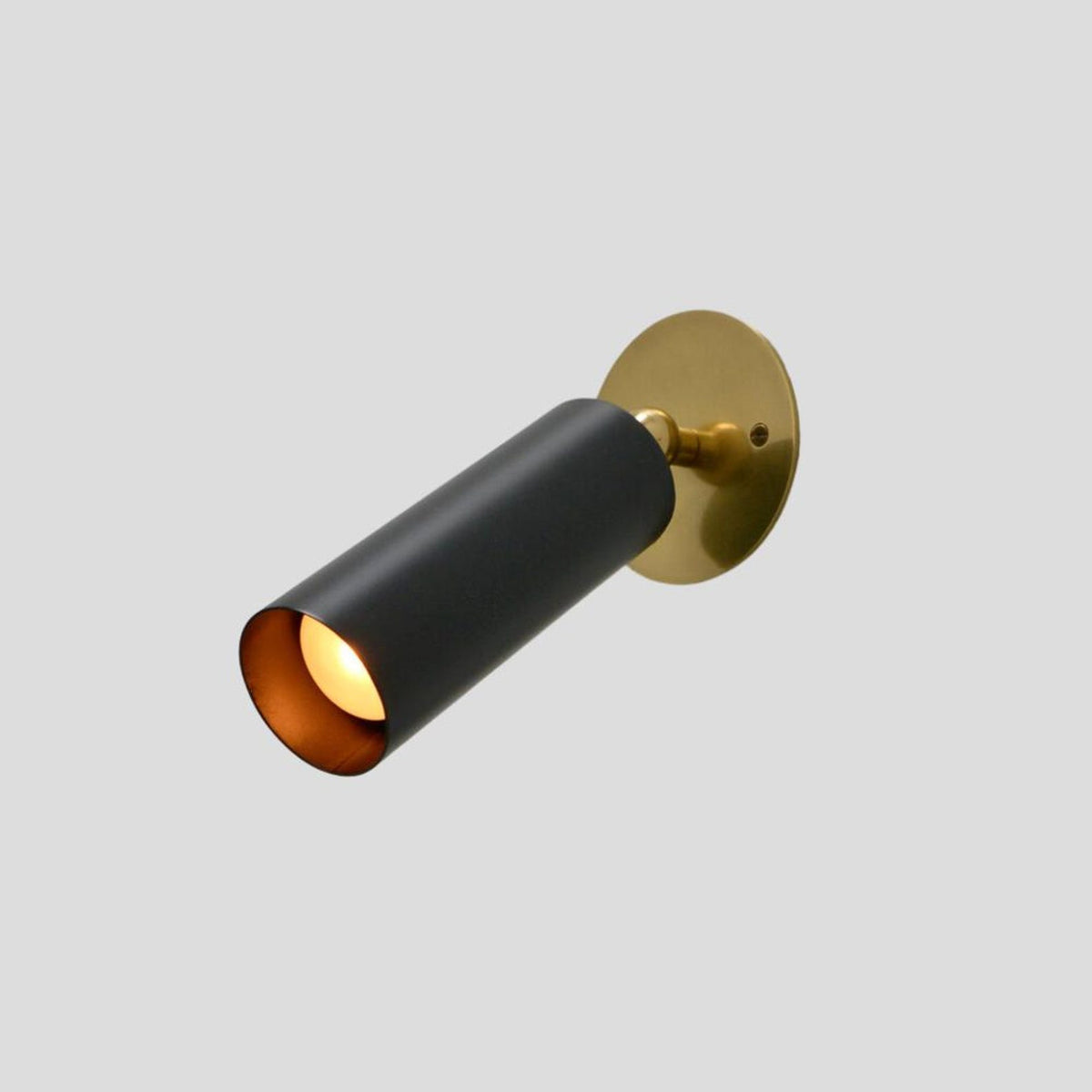 Handmade black brass wall light with long cylindrical body and golden base plate