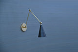 Black cone adjustable brass wall sconce with swing arm, mounted on blue wall