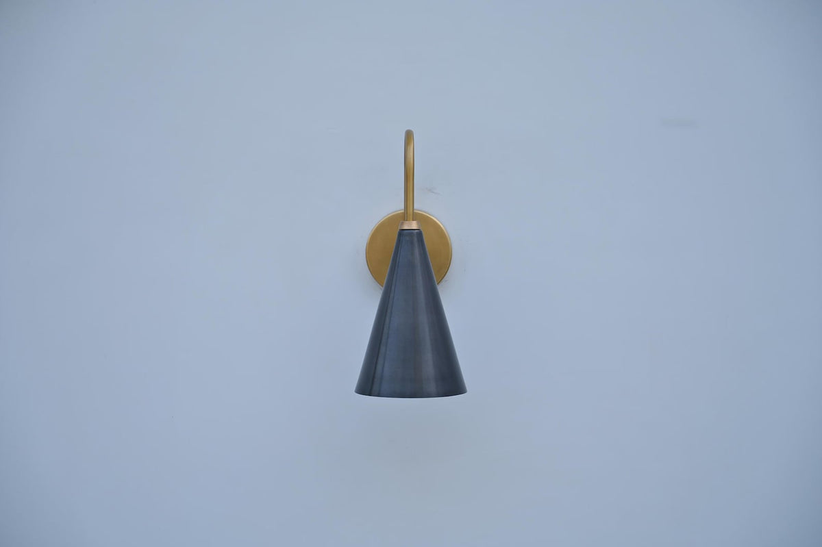 Front view of handcrafted brass wall sconce featuring a sleek black cone shade and warm brass frame