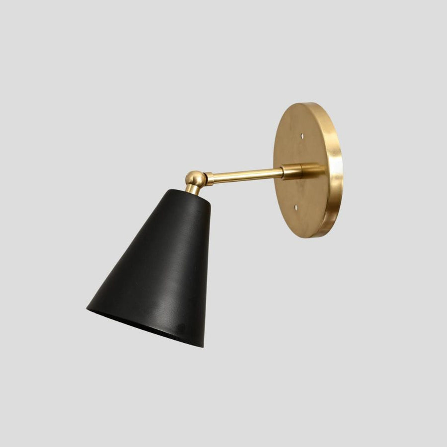 Modern black cone wall sconce with solid brass base, handmade industrial lighting fixture, side angle view.