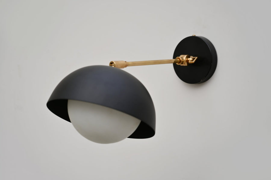 Side view of black dome wall light with brushed brass arm and matte black round mount, handcrafted by Brass Leaf Studio.