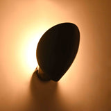 Black petal wall sconce side view with curved solid brass shield and round wall backplate