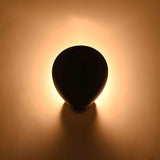 Black solid brass ambient wall light with rounded petal form and warm decorative halo effect
