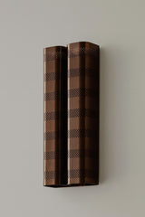 Blackened brass perforated wall sconce with industrial modern design mounted on neutral wall