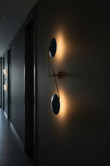 Blue round shade wall sconce side view showing slim brass arm structure and artistic vertical design