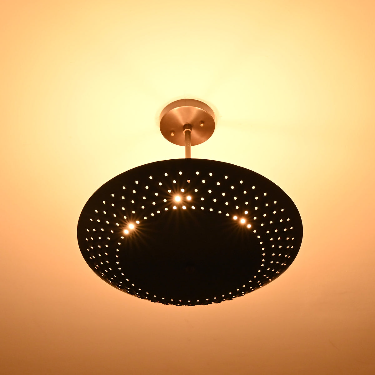 Bottom view of illuminated brass disc chandelier radiating indirect warm light