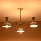Brass 3-light chandelier illuminated with warm ambient lighting, featuring white bowl-shaped shades