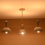 Mid-century brass 3-light chandelier emitting soft warm glow, handcrafted by Brass Leaf Studio.