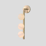 Handmade brass wall sconce with three frosted glass globe shades, modern vertical light fixture front view