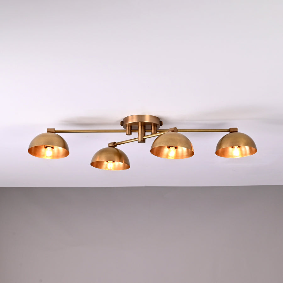 Handmade brass ceiling light with four dome-shaped shades illuminated, modern low-profile 4-light fixture for living room or hallway.