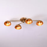 Contemporary 4-light brass flushmount chandelier featuring adjustable arms and warm glowing dome shades, minimalist ceiling light.