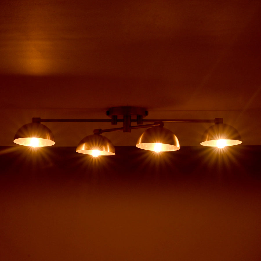Handmade brass ceiling light with four dome-shaped shades illuminated, modern low-profile 4-light fixture for living room or hallway.