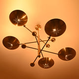 Illuminated brass chandelier with five celestial perforated shades casting warm ambient light.