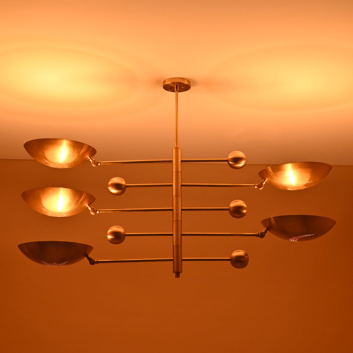 Overhead view of 5-light brushed brass chandelier emitting soft warm glow on ceiling.