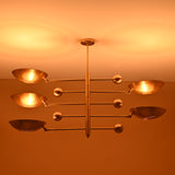 Overhead view of 5-light brushed brass chandelier emitting soft warm glow on ceiling.