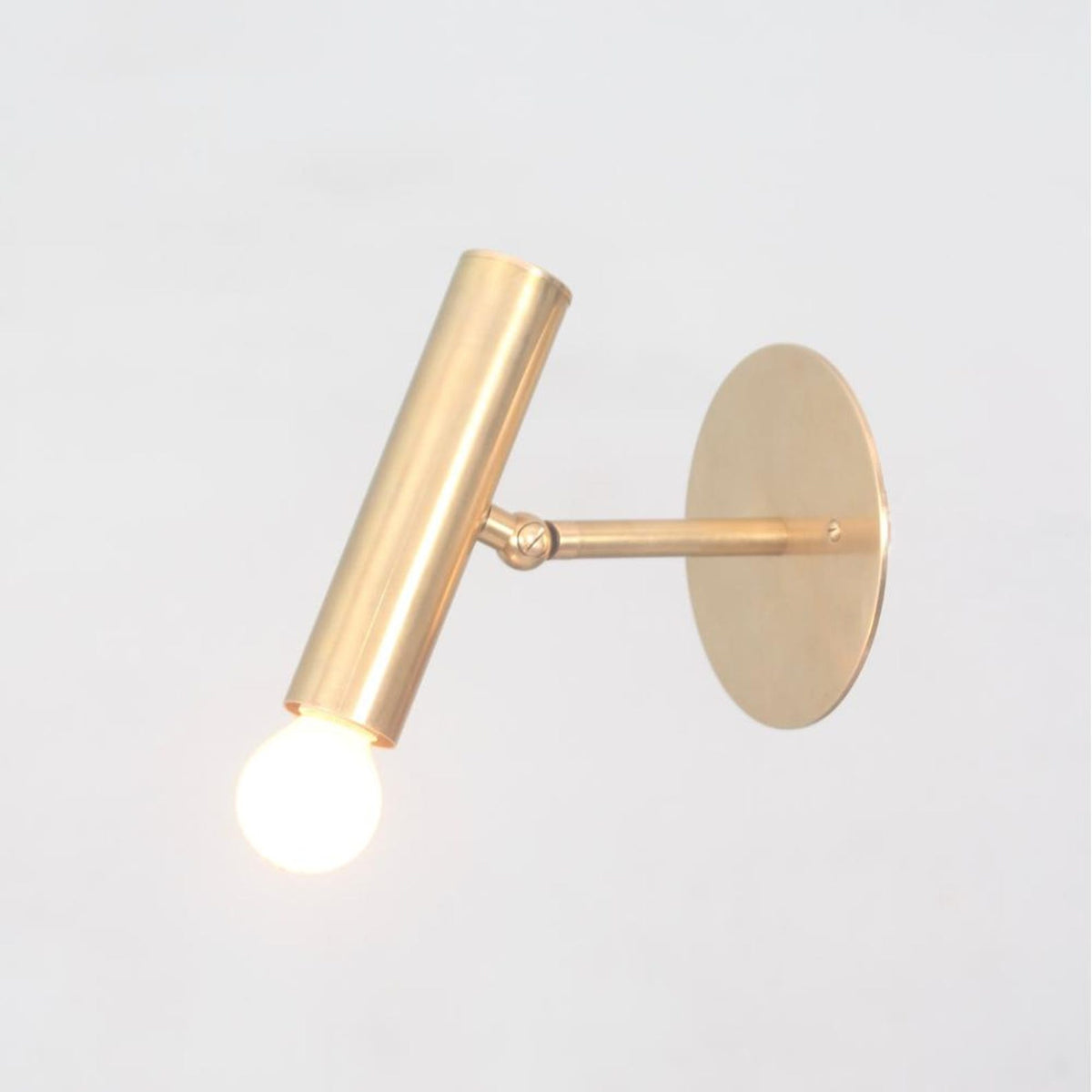 Minimalist brass adjustable spotlight with cylindrical shape and swivel arm for directional lighting