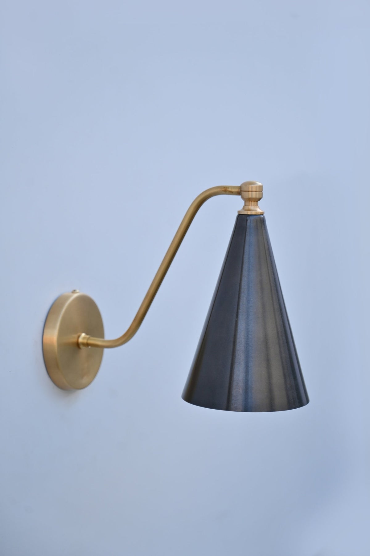 Sleek side profile of brass and blackened cone wall sconce, handcrafted with a refined matte finish.