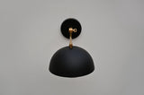 Top angle view of brass arm and matte black dome wall sconce showing clean geometry and handcrafted detailing.
