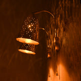 Angled view of brass bell wall sconces glowing, creating patterned reflections on the wall