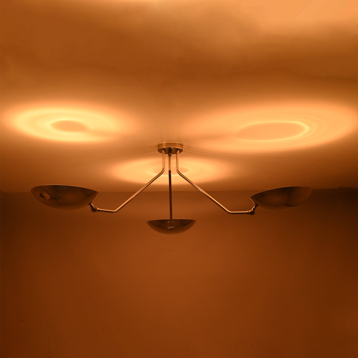 Warm ceiling reflections created by polished chrome brass bowl ceiling light with indirect lighting design.