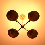 Bottom-up glowing view of brass bowl chandelier, showing four darkened bowl interiors creating a warm halo lighting effect on the ceiling.