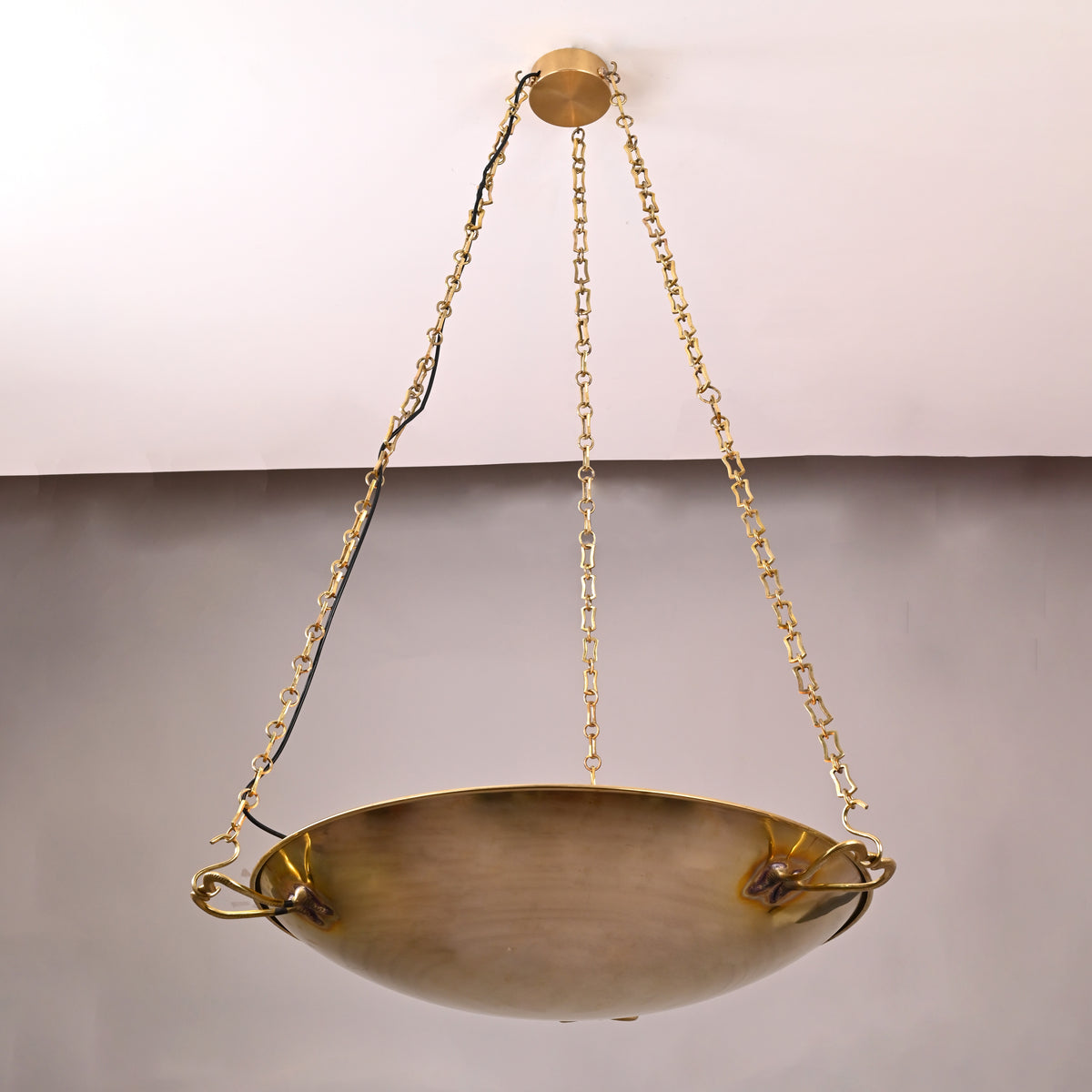 Close-up of suspended brass bowl showing handcrafted texture and solid brass chain mounts