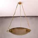 Close-up of suspended brass bowl showing handcrafted texture and solid brass chain mounts