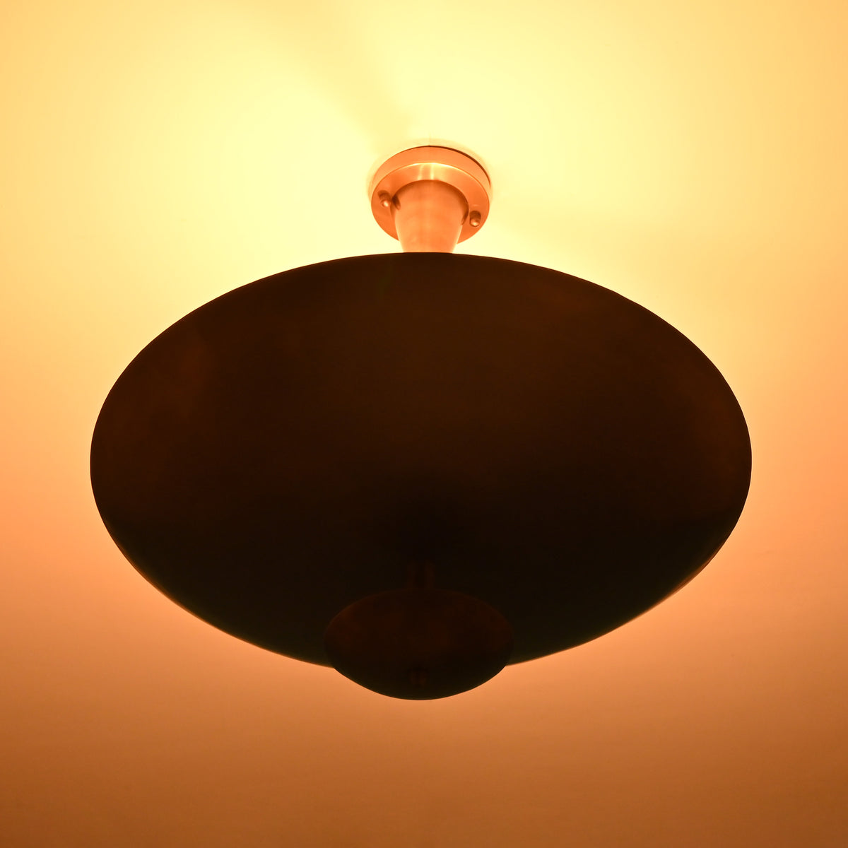 Brass bowl disc chandelier in low-light setting highlighting warm ceiling glow, sculptural form, and elegant minimalist presence
