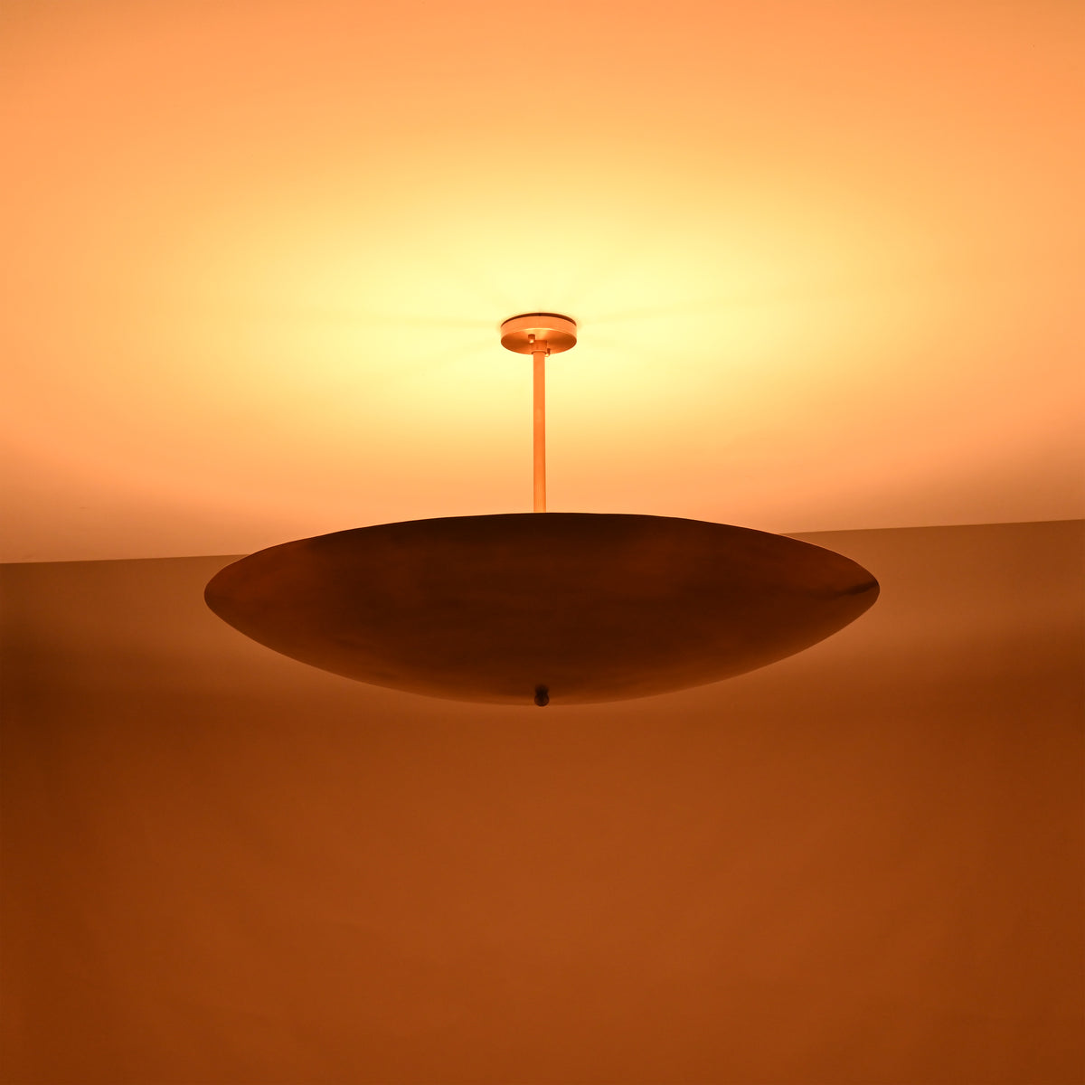 Warm night view of brass bowl pendant light casting soft ambient uplighting onto the ceiling.