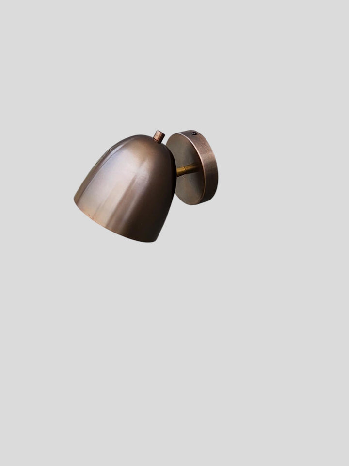 Side angle view of handcrafted brass wall sconce in antique patina finish, minimalist industrial design