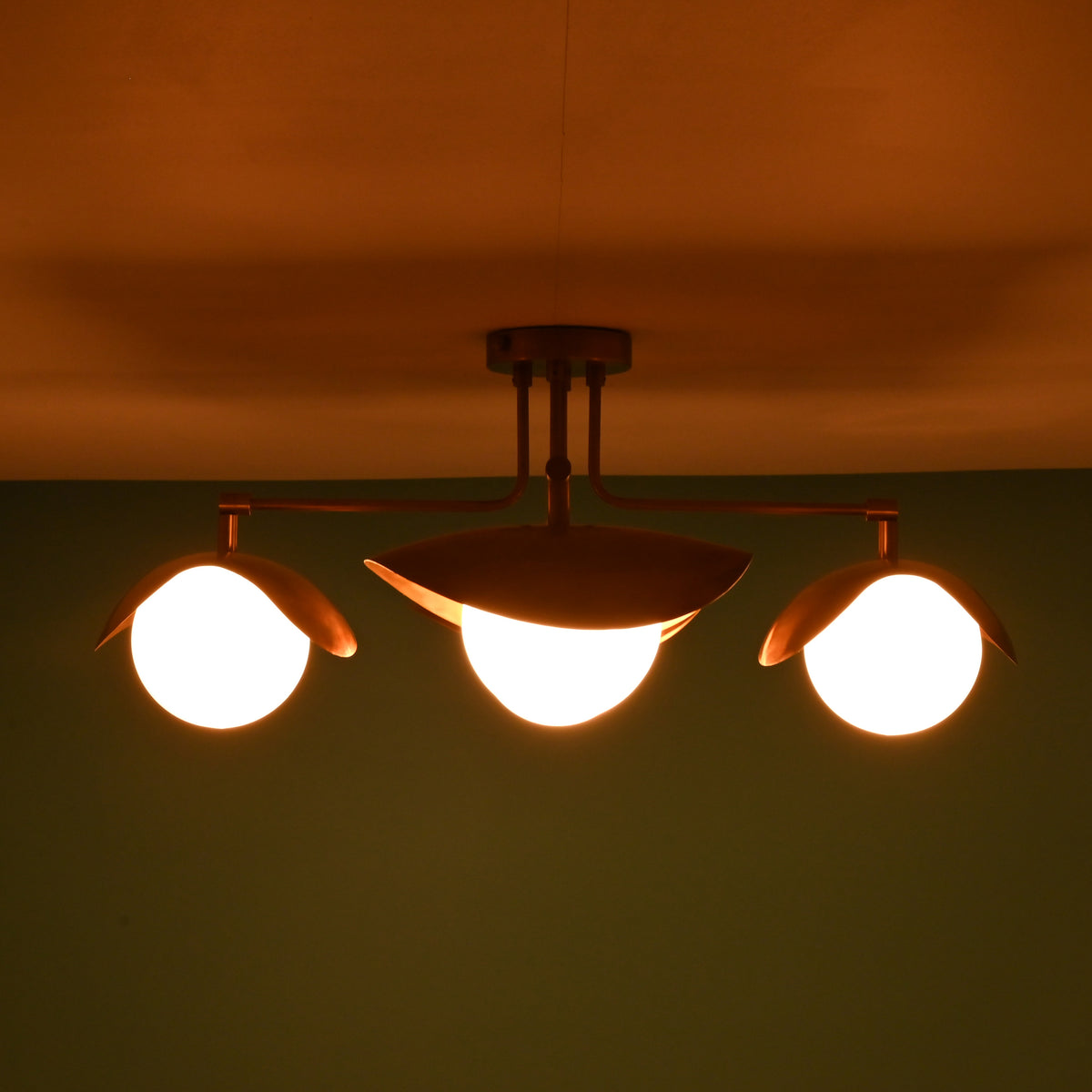 Brass flush mount ceiling light glowing warmly with four frosted glass globes.
