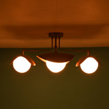 Brass flush mount ceiling light glowing warmly with four frosted glass globes.