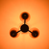 Warm-lit bottom view of brass ceiling light with three sculpted cups and soft ambient illumination.