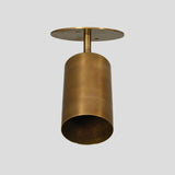 Minimalist brass ceiling spotlight viewed from below, featuring cylindrical body and round mount plate