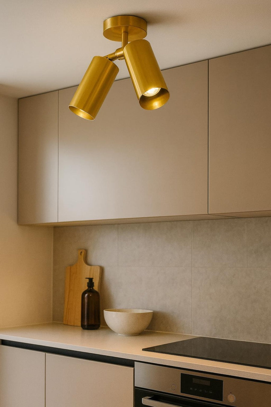 Modern brushed brass double cylinder ceiling spotlight with adjustable heads mounted on white ceiling in contemporary interior.