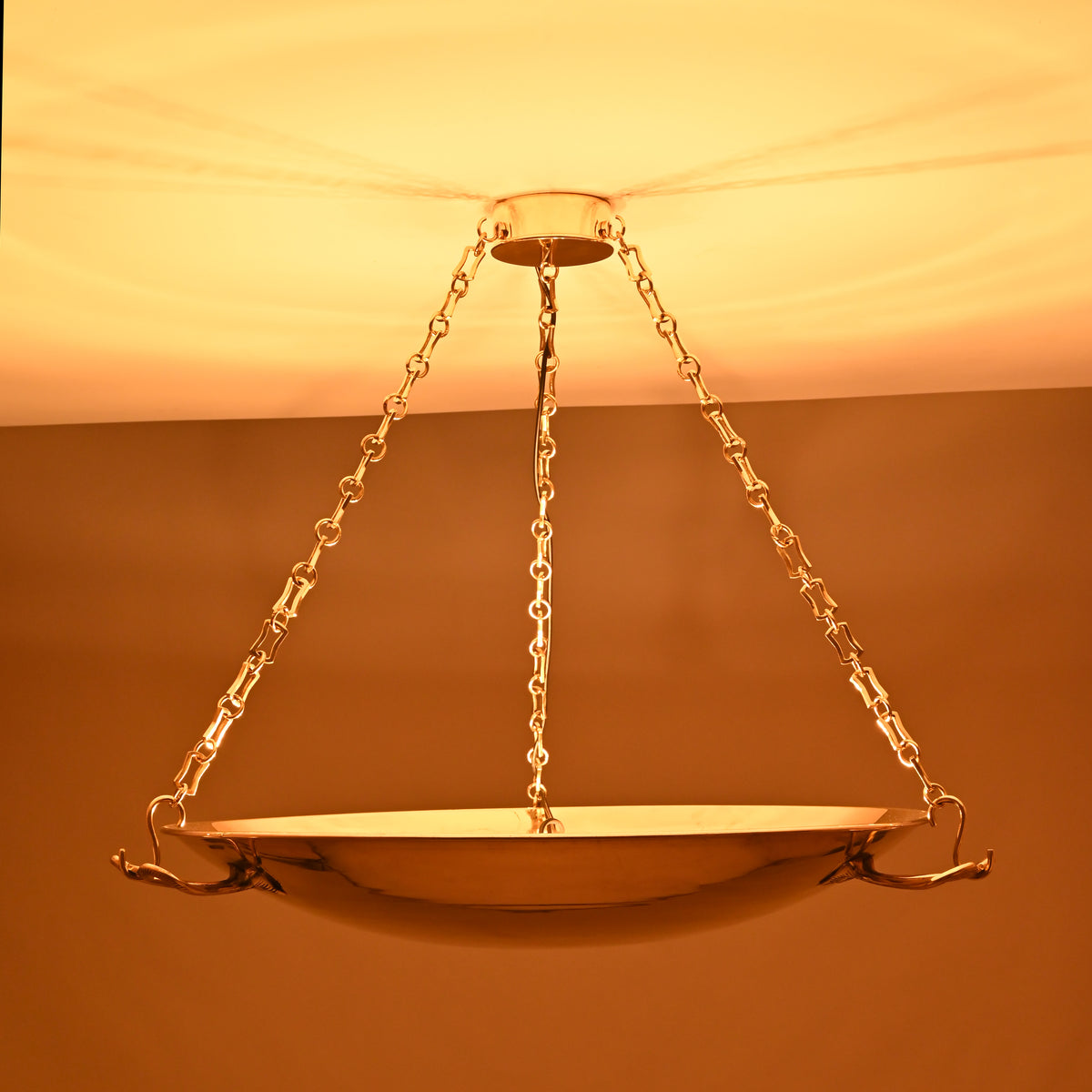 Chain-hung solid brass chandelier with sculpted handles and polished finish, reflecting classic design